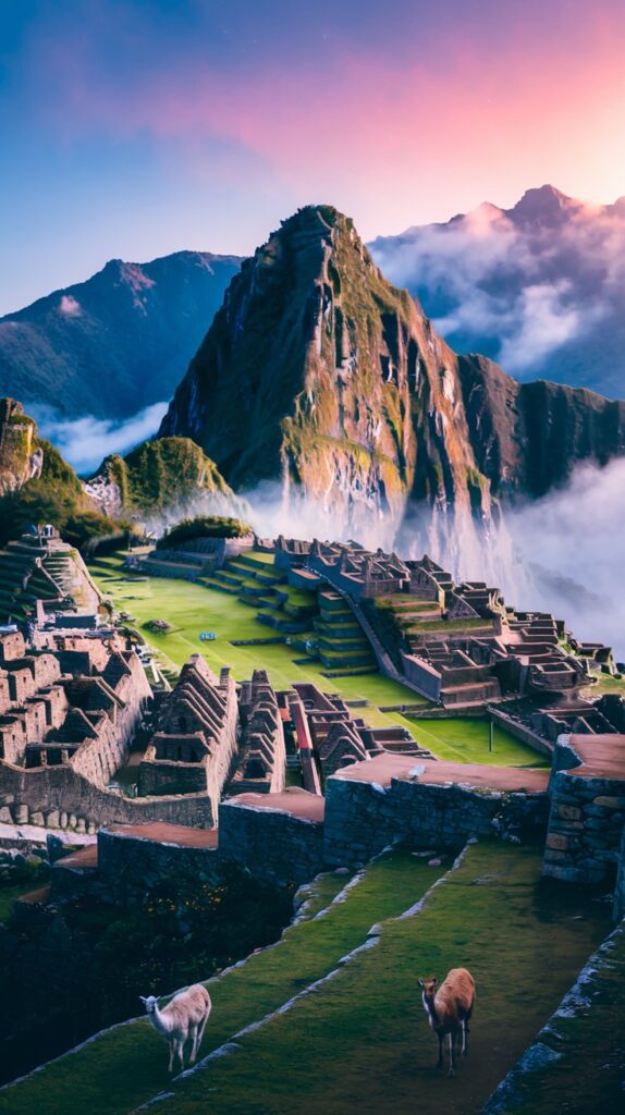 Sunrise over Machu Picchu with ancient stone ruins and misty mountains.

